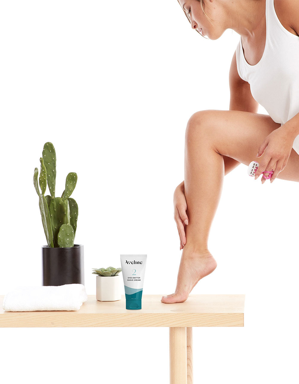 Woman applying cream to her leg with a cactus plant and towel in the background